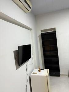 a room with a tv on a white wall with a table at Hotel Amazon In in Belém