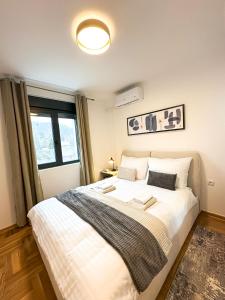 a bedroom with a large white bed with a window at NEPTUN Apartments in Vrnjačka Banja