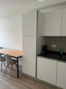a kitchen with white cabinets and a wooden table at Appartement Famille in Geneva