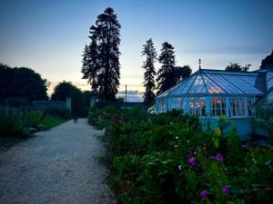 a greenhouse in front of a garden with purple flowers at The carriage in Three Cocks Junction