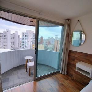 a room with a balcony with a view of the city at Flat Completo Suíte com Terraço, Cozinha, Garagem Manobrista Liberdade, Paraíso 24h in São Paulo