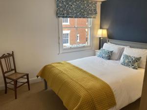 a bedroom with a bed and a chair and a window at Witcroft Cottage in Pershore