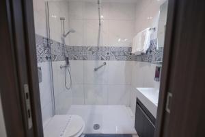 a white bathroom with a shower and a toilet at The Exiles Hotel in Sliema