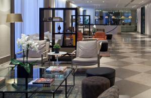 eine Lobby mit einem Wartebereich mit Stühlen und Tischen in der Unterkunft Hotel Berlin Potsdamer Platz by Leonardo Hotels in Berlin