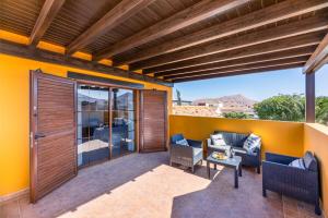 Un patio con paredes amarillas y una pérgola de madera. en Villa Calma Private Pool La Oliva By Holidays Home, en La Oliva
