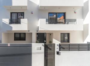 a white house with a gate and a balcony at Fly & Stay in Artemida