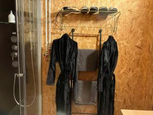 a bathroom with a shower with black coats on a rack at La St masphair in Sainte-Marie +10 photos