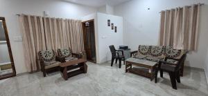 a living room with chairs and a table at Chiraanya Service Apartment in Chikmagalūr