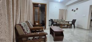 a living room with chairs and a couch and a table at Chiraanya Service Apartment in Chikmagalūr +15 photos