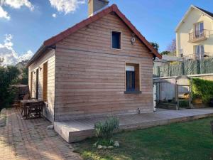 a small house with a wooden deck in a yard at Maisonnette Individuelle in Carpiquet