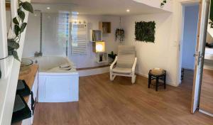 a bathroom with a tub and a chair in a room at Maisonnette Individuelle in Carpiquet
