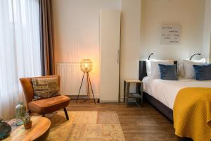 a bedroom with a bed and a chair and a table at Oranjestaete Boutique Hotel & Apartments in Nijmegen