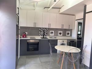 a kitchen with white cabinets and a table and chairs at 122 Shearwater - Nora's Place in Sedgefield