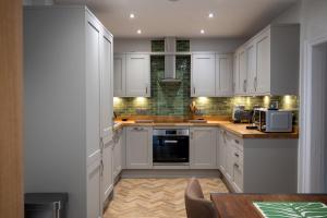 a white kitchen with white cabinets and a table at 2 Bed Ironbridge in Ironbridge