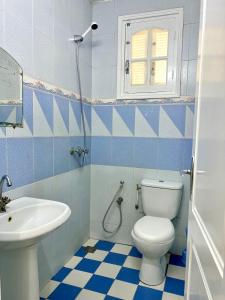 a blue and white bathroom with a toilet and a sink at Family-Friendly Studio in Mahdia