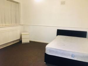 an empty room with a bed and a night stand at Goldicroft House Road in Wednesbury