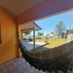 a hammock in a house with a view of a yard at Paraíso em torres in Torres +3 photos