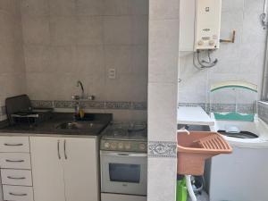 a small kitchen with a sink and a stove at Perto Consulado Americano Ar QUENTE 2 quartos Até 6 pessoas Av Carlos Gomes não tem garagem in Porto Alegre