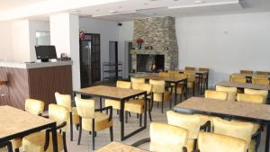 a dining room with tables and chairs and a fireplace at Gostionica Tava in Tuzla