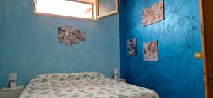 a bedroom with a blue wall with a bed at Kenzia in Agnone Bagni