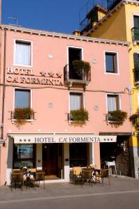 a pink building with tables and chairs in front of it at Hotel Ca' Formenta in Venice