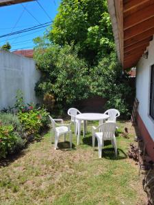 four white chairs and a table in a yard at Departamento - Casa en Mar del Tuyú in Mar del Tuyú