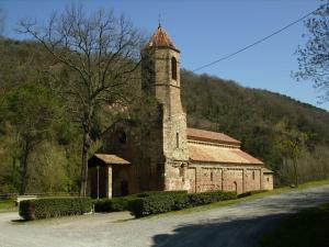 an old stone building with a tower on a hill at Pensió L'Estada in Sant Joan les Fonts