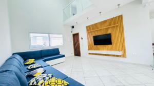 een woonkamer met een blauwe bank en een tv bij Martin de Sá-200 metros da praia in Caraguatatuba