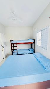 een slaapkamer met een bed met blauwe lakens en een raam bij Martin de Sá-200 metros da praia in Caraguatatuba +42 foto's