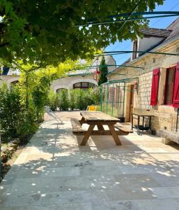 a wooden picnic table sitting on a patio at Maison d'Antan - PiscineJardinClim - Bourg de Cuzance in Cuzance