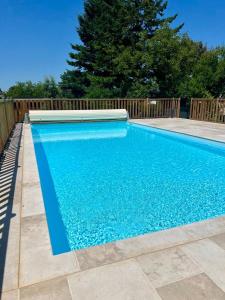 a swimming pool next to a wooden fence at Maison d'Antan - PiscineJardinClim - Bourg de Cuzance in Cuzance