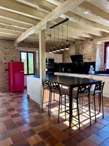 a kitchen with a black table and chairs and a red refrigerator at Maison d'Antan - PiscineJardinClim - Bourg de Cuzance in Cuzance