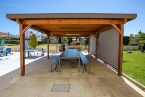 un padiglione in legno con tavolo e panche su un patio di Stunning Villa with Heated Pool, Garden, BBQ a Quarteira