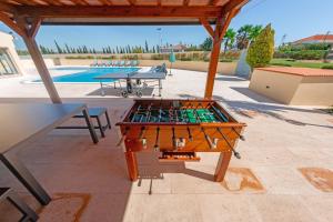 un tavolo da ping pong su un patio accanto alla piscina di Stunning Villa with Heated Pool, Garden, BBQ a Quarteira