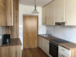 a kitchen with white cabinets and a wooden door at Sobe apartma Dobe in Bled