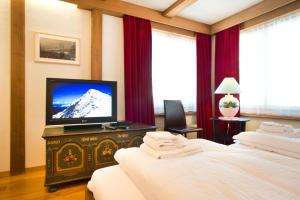 a bedroom with two beds and a flat screen tv at Bernerhof Residence in Grindelwald