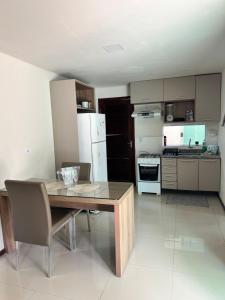 a kitchen with a wooden table and a white refrigerator at LENÇOIS VILLE RESIDENCE in Barreirinhas