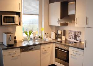 a kitchen with white cabinets and a sink at Meeresrauschen 6 in Großenbrode