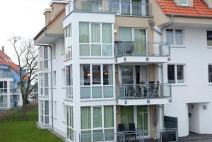 a white apartment building with balconies and tables at Meeresrauschen 6 in Großenbrode +10 photos