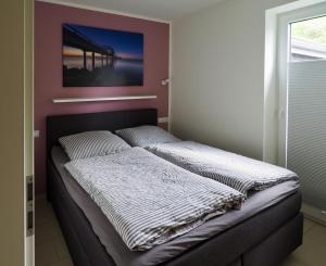 a bed in a bedroom with a picture on the wall at Kirschgarten 2 - Möwennest in Kellenhusen