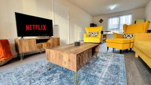 a living room with a flat screen tv and yellow chairs at Modern New Build 3-Storey Home with Parking near Leicester City Centre in Leicester