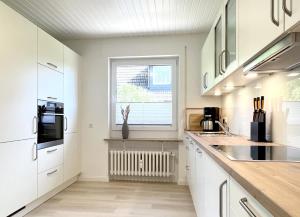 a kitchen with white cabinets and a window at Lütte Deern in Kellenhusen
