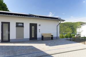 ein weißes Haus mit einer Bank auf einer Terrasse in der Unterkunft Haus Seeblick - Sonnenweg 14 in Diemelsee + 17 Fotos