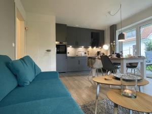 a living room with a blue couch and a kitchen at Dahmer Strand 1 - LÜTT HUIS in Dahme