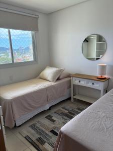a bedroom with two beds and a mirror and a window at Vista inesquecível para o mar homeclub BetoCarrero in Penha +41 photos