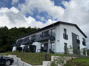 una casa blanca con balcones y un coche aparcado delante en Sonnenweg 48-5 - HARMONIE, en Heringhausen