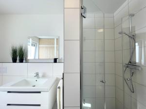 a white bathroom with a sink and a shower at Dahmer Strand 7 in Dahme +19 photos