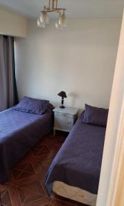 a bedroom with two beds and a lamp on a night stand at Céntrico Depto - Viña del Mar in Viña del Mar