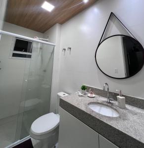 Un baño con inodoro, lavabo y espejo. en Unitá Praia Grande Boqueirão, en Praia Grande