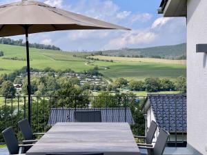 a table with an umbrella and chairs on a balcony at Diemelblick 23 - DIEMELTJE in Heringhausen